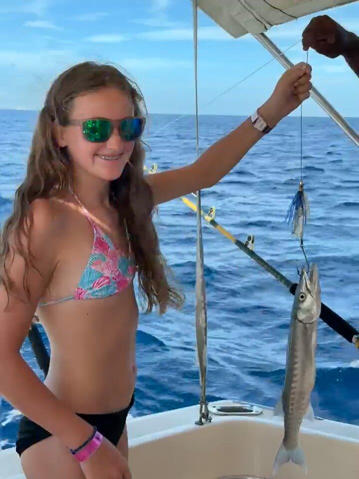 Smiling young guest holding her catch aboard Mutton Fish Tours